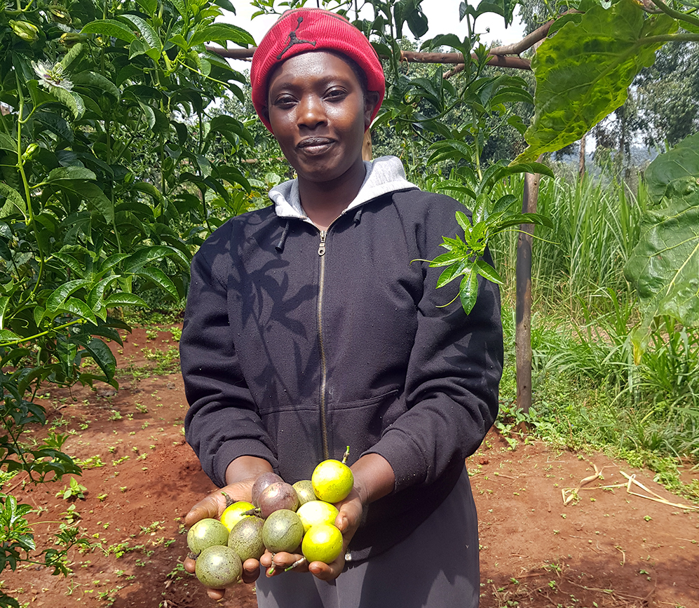 Margaret holding harvested fruit from her Forest Garden.