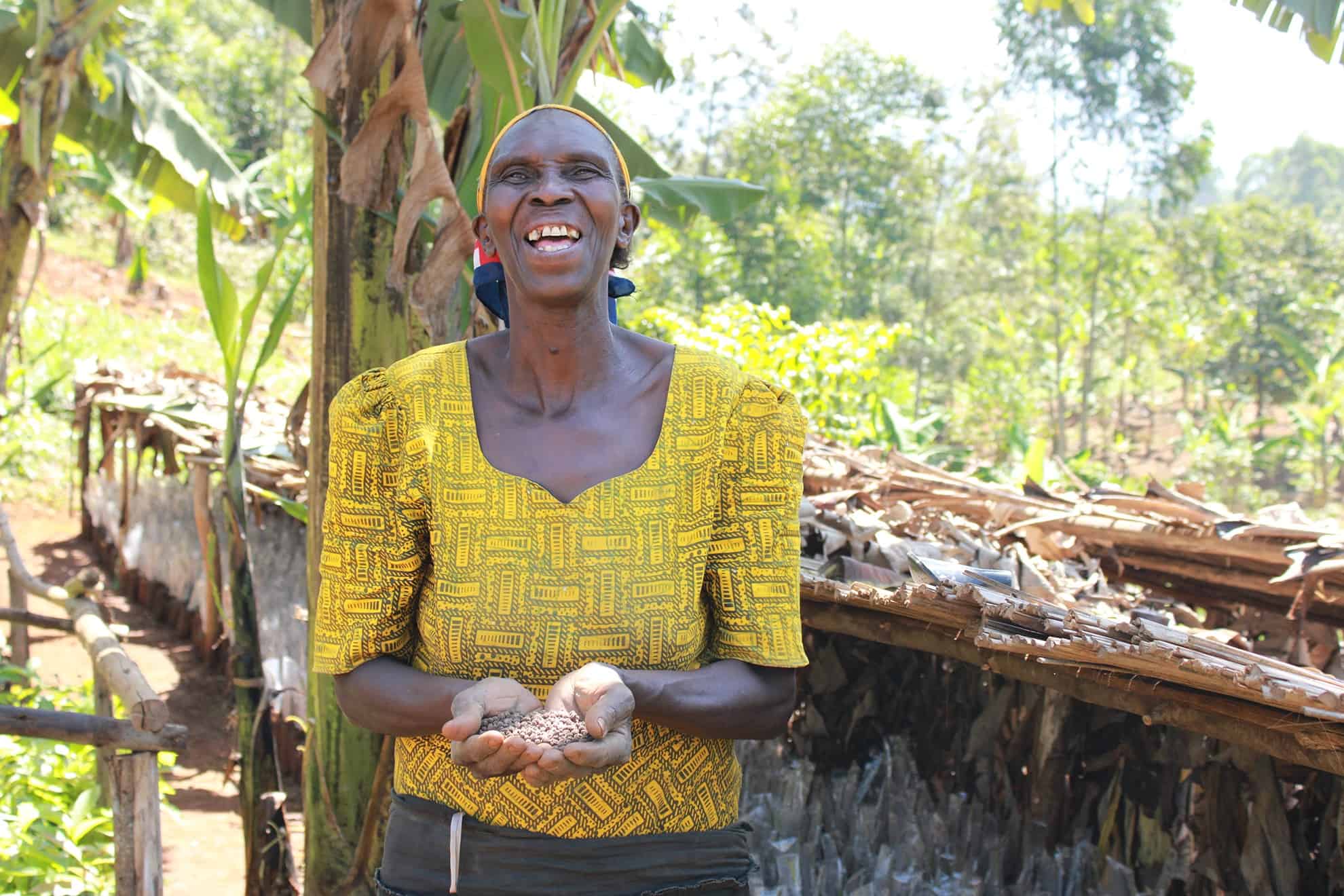 A smiling woman proudly holding seeds, symbolizing the positive outcomes highlighted in TREES' 2021 Impact Report.
