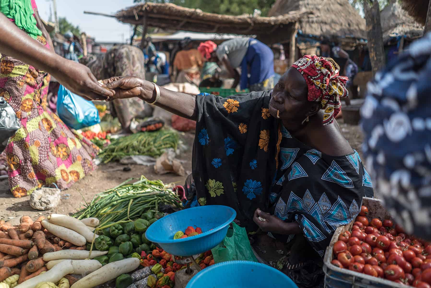 Women exchanging goods at a vibrant local vegetable market.