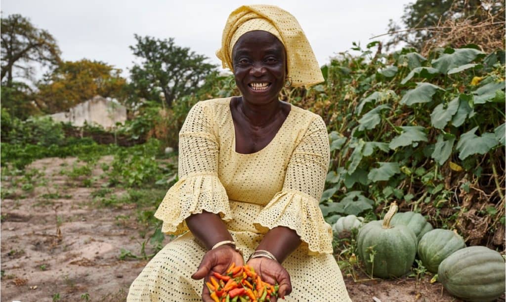 Smiling woman proudly displays harvested peppers.